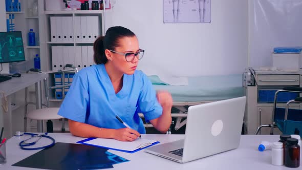 Exhausted Assistant Staring at Laptop Screen Wrinting on Clipboard