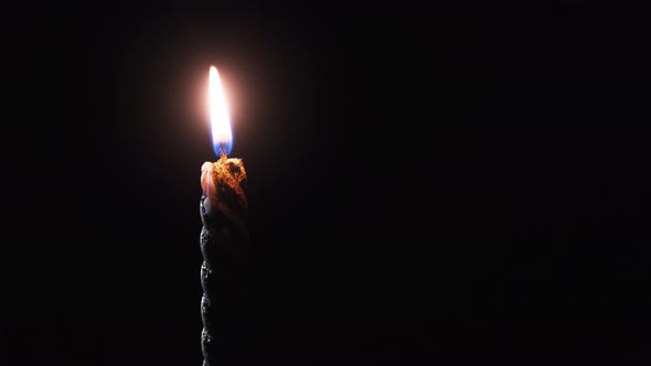 A Single Candle Is Lit on a Black Background. Candle Flame in the Dark.