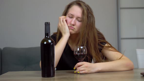 woman is sad and devastated alcoholic sitting at home on couch drinking red wine