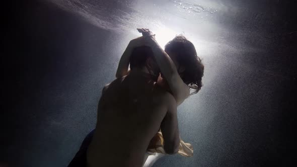 A Man Passionately Embraces and Touches His Woman Underwater Lovers Deep Inside on a Dark Background