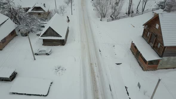 Fast Flight Over a Road in Carpathian Village. Bird's Eye View of Snow-covered Houses