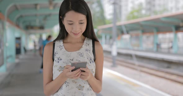 Woman using mobile phone in Hong Kong light rail station 