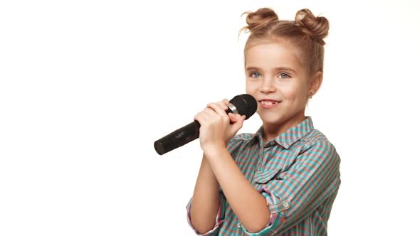 Charming Caucasian Small Kid Girl in Pladi Checking Black Microphone Then Singing on It Smiling on