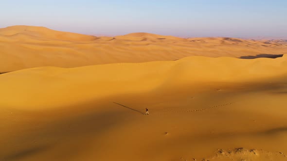 Aerial view of a man walking on dunes during the sunset, U.A.E.