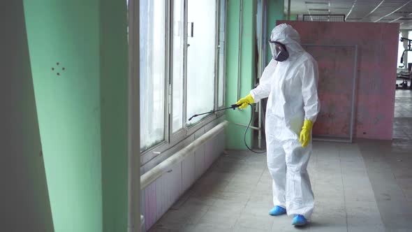 Exterminator in Overalls and a Protective Mask Carries Out Processing of the Room