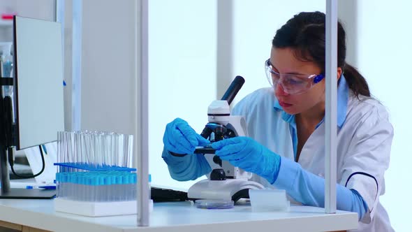 Scientist Placing a Slide on Specimen Stage of a Laboratory Microscope