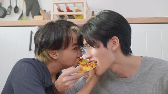 Asian young handsome man gay couple sit on floor and eating pizza together. Homosexual-LGBTQ concept