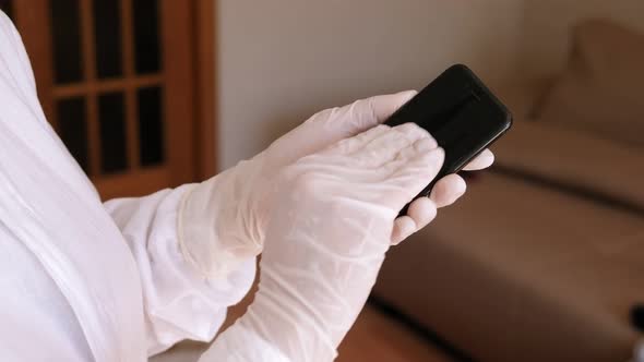 Woman in Gloves Disinfecting Phone with Antiseptic Wet Wipe