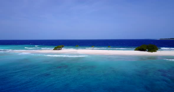 Wide overhead tourism shot of a white sandy paradise beach and blue water background in colourful 4K