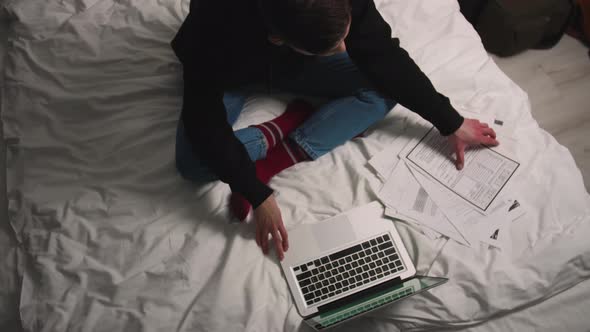 Man working with Documents using laptop on Bed
