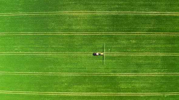 Tractor spraying the chemicals on the green field, aerial view