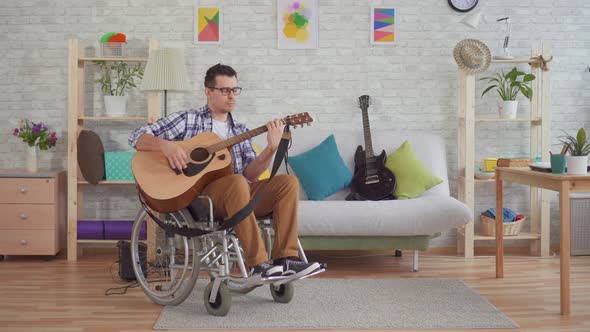 Young Disabled Man in a Wheelchair Musician Plays Guitar