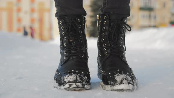 Female Feet in Black Boots Winter Walking in Snow