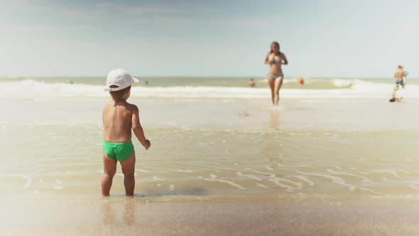 Kid Collects Shells and Pebbles in the Sea on a Sandy Bottom Under the Summer Sun on a Vacation