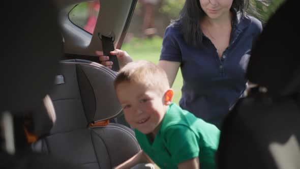 Mom and Son Go to the Car the Child Gets Into a Child Car Seat