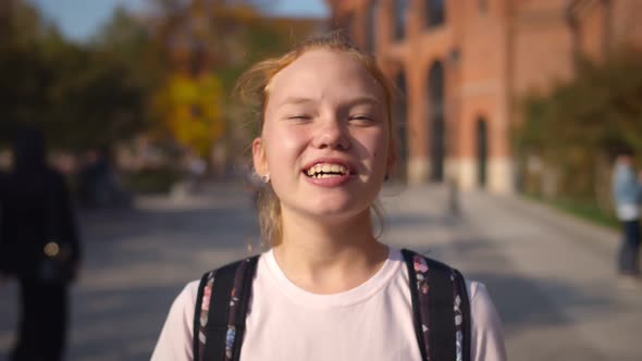 Close Up Portrait of Happy Laughing Redhead Schoolgirl Standing Outdoors