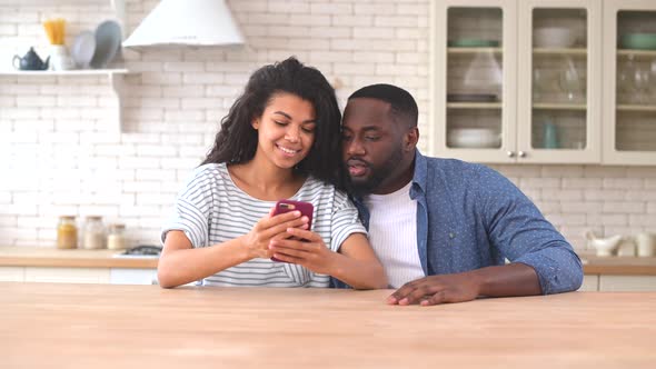 Happy Multiracial Couple Using a Smartphone at Home