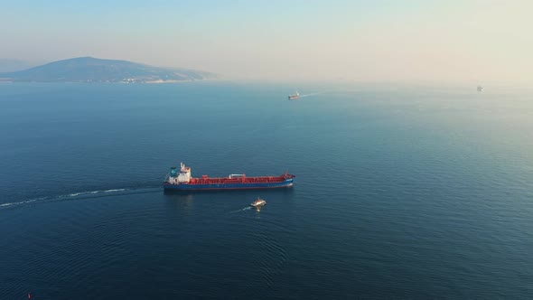 Aerial View Following the Ultra Large Cargo Ship at Sea Leaves Port at Sunset