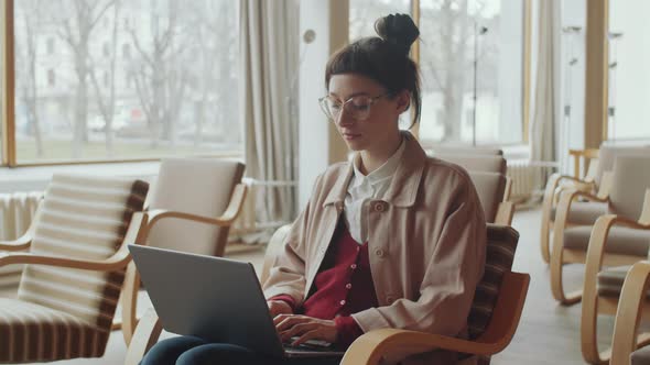 Young Woman Working on Laptop in Library Auditorium