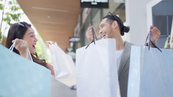 Portrait of Asian man and woman shopping outdoors in department store.