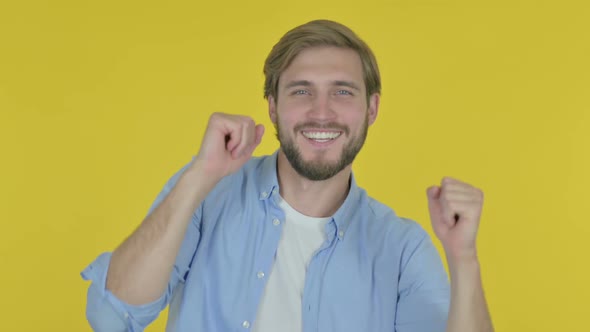 Young Man Dancing in Joy on Yellow Background