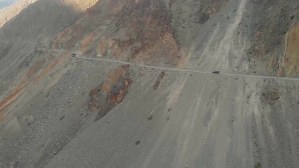 Cars Driving Along Winding Mountain Road At Shandur Pass In Pakistan. Aerial Follow Shot Slow Motion