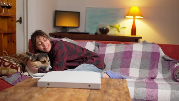 Tender Woman Sits on Couch with Dog Hugging and Petting Him