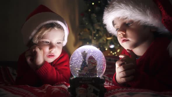 Cute Little Boys in Santa Hats with Snow Globe