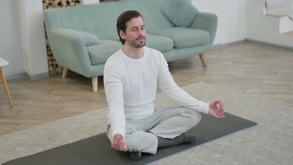 Top View of Young Man Meditating on Yoga Mat at Home