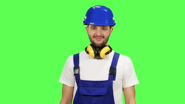 Builder Holds a Drill in His Hands and Looks Around. Green Screen