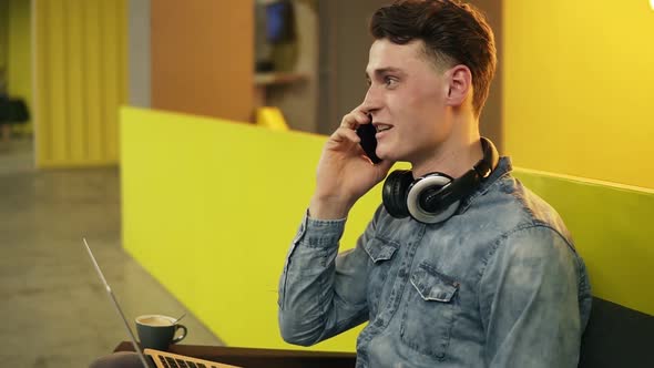 Attractive Sexy Young Guy in Demin Shirt Sitting in Well Lit Indoors Space Talking to Someone on the