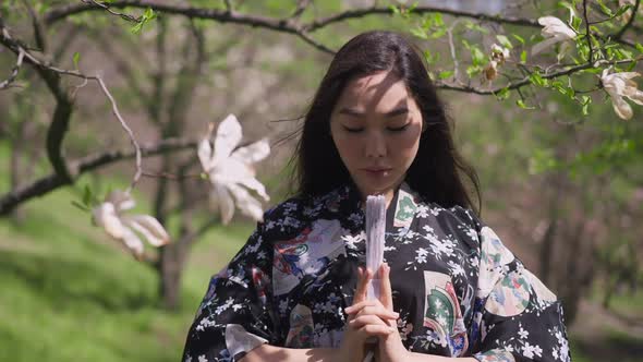 Front View Portrait of Young Confident Asian Beautiful Woman Holding Closed Fan Looking at Camera