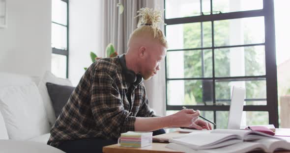 Albino african american man with dreadlocks working and using laptop