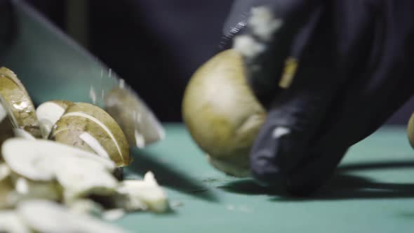 Cook's Hands in Black Gloves Slicing Mushrooms Close Up Selective Focus