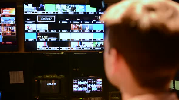 Rack focus close up perspective shot of man looking at television studio camera feeds