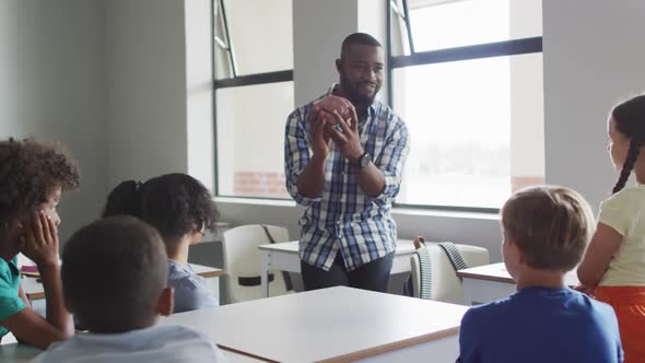 Video of happy african american male teacher and class of diverse pupils during biology lesson