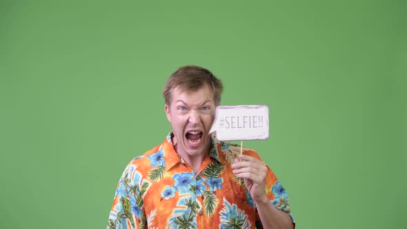 Young Handsome Tourist Man Screaming with Selfie Paper Sign