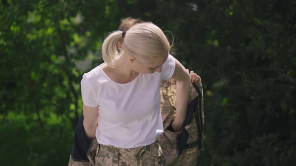 Loving Teenage Son Putting Camouflage Jacket on Military Mother in Slow Motion Outdoors