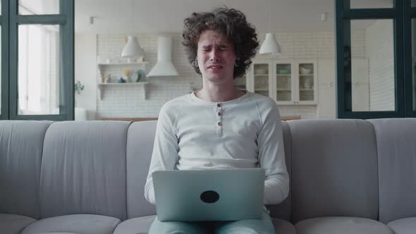 Stressed Curly Guy Working at Home on Laptop