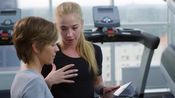 Fitness Trainer Talking to Female Client