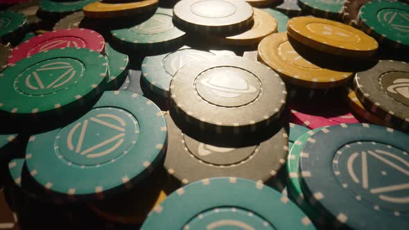 Heap of Colored Casino Chips on a Dark Backlit Table