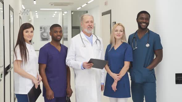 Confident Senior Doctor in White Uniform and Young Doctors Therapists Posing Looking at Camera