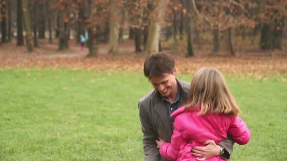 Girl running into father's arms in park
