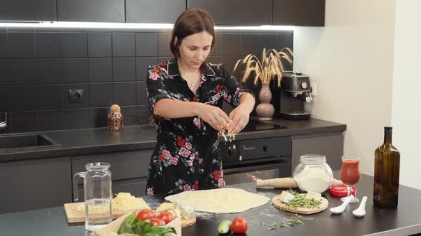 Woman sprinkling cheese on pizza base, making Quattro cheese pizza