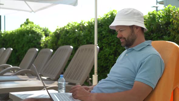 Man working on laptop on a sun lounger