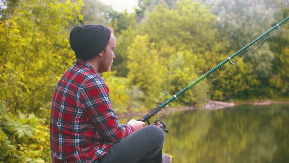 Young Man Sitting on Fishing - Pulling the Rod and Spinning the Roulette