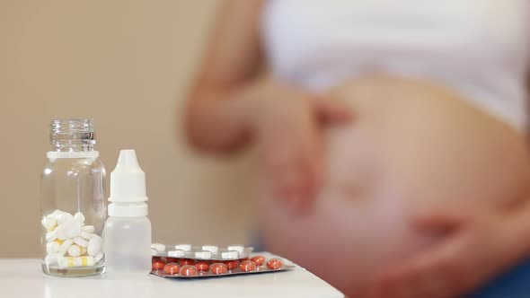 Medical drugs and a pregnant girl rubbing her belly on the background.