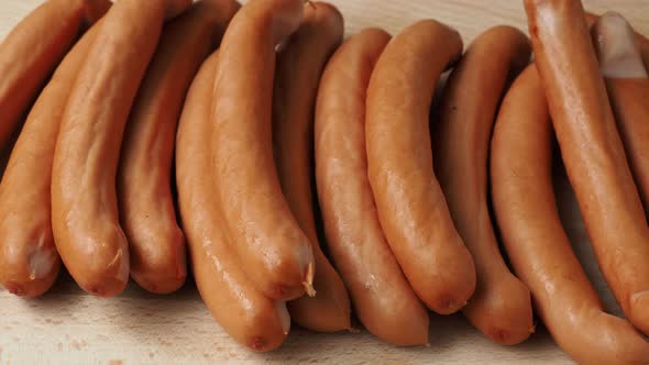 Thin long pork sausages on the wooden cutting board