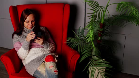 Woman Sitting in Armchair with Smartphone
