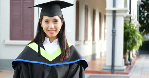 Asian woman wearing graduation gown
